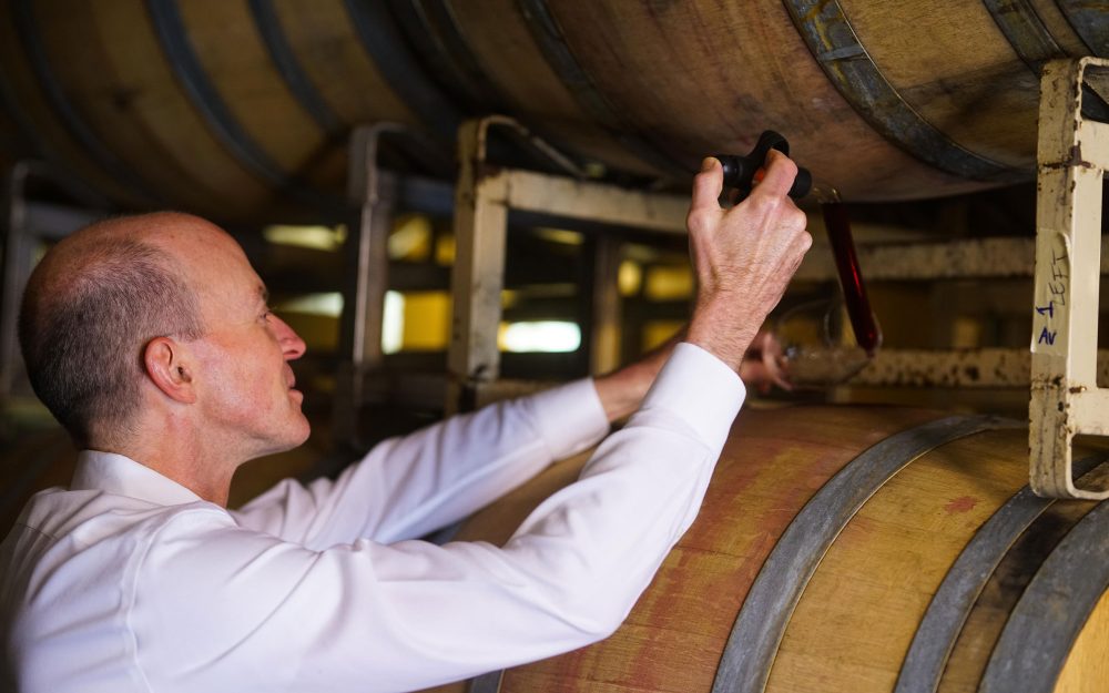 Man pulling wine from a barrel